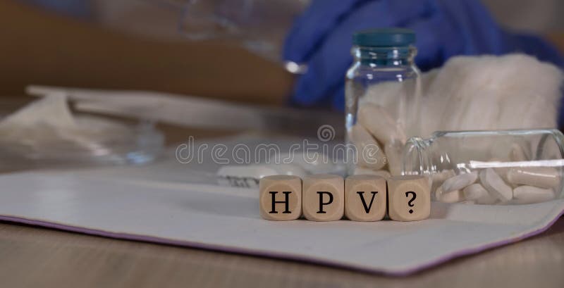 Abbreviation HPV with question mark for human papilloma virus infection composed of wooden dices. Pills, documents and a pen in. Abbreviation HPV with question royalty free stock images