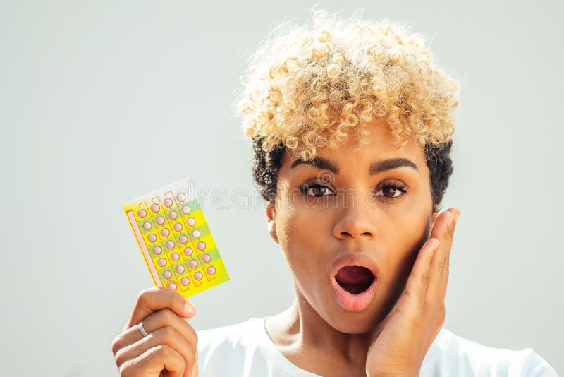 Beautiful surprise african american woman holding birth control tablet and open mouth becouse she forgot to take the. Pills on time. toothache concept stock photos
