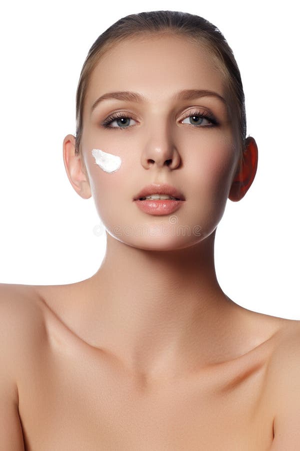 Beauty face of young woman. Beauty face of young woman with cosmetic cream on a cheek. Skin care concept. Closeup portrait. Isolated on white. Young woman with stock photography