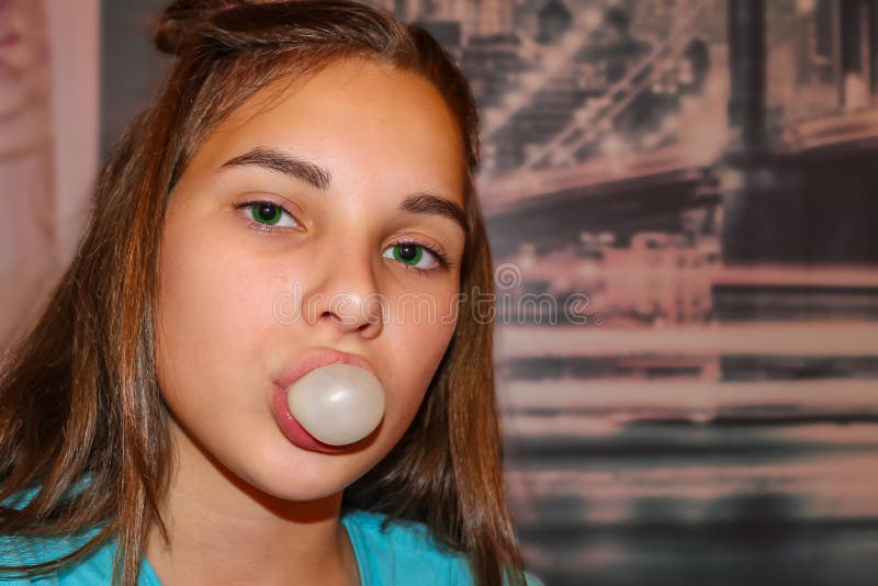The cheeky girl is a teenager. Portrait of a modern girl with an impudent look. Long fair-haired hair, green eyes. In the mouth a bubble of chewing gum. The royalty free stock photography