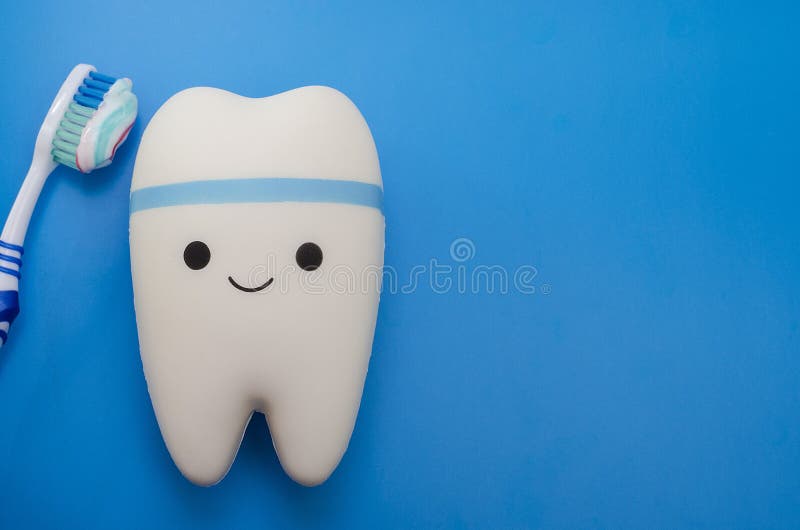 Cheerful smiling tooth on a blue background with a toothbrush with copy space. Pediatric and adult dentistry. Dental treatment and royalty free stock image