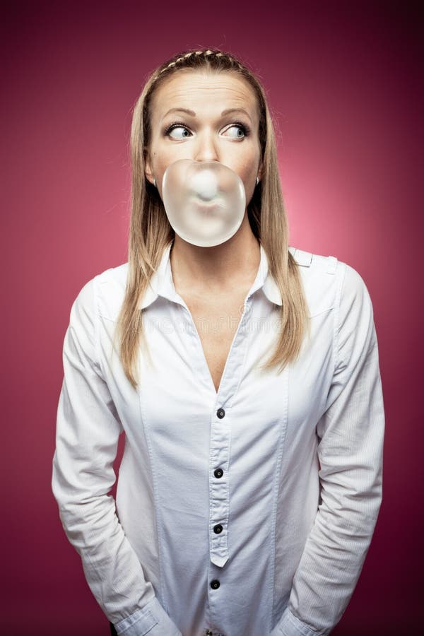 Chewing gum. Young woman making a chewing gum bubble and looking right stock photo