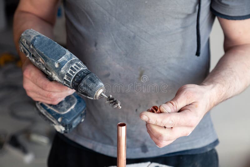 Closeup worker plumber master cleaning copper pipes with professional brush. Concept installation, changing pipeline, solder flux. Paste, professional repair stock photo