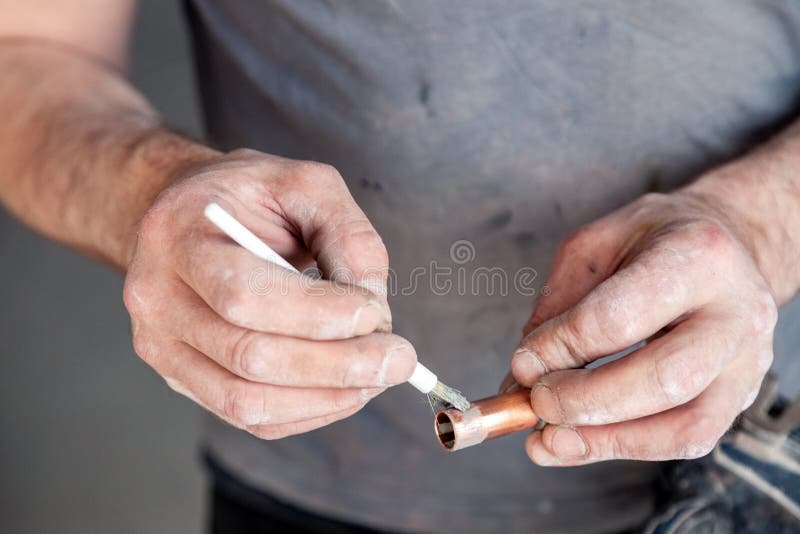 Closeup worker plumber master cleaning copper pipes with professional brush. Concept installation, changing pipeline, solder flux. Paste, professional repair royalty free stock images