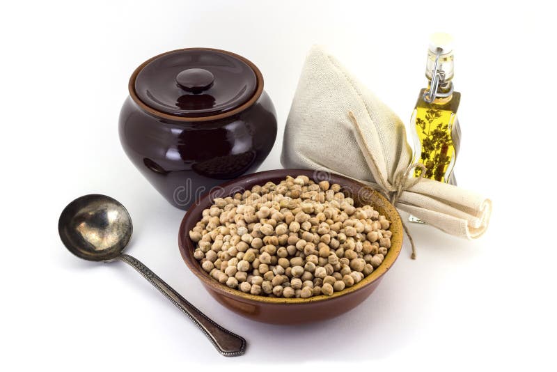 The composition of chick peas in a clay pial next to a clay pot and a copper spoon,. Still life of chick peas in ceramic pial, ceramic pot, old spoon and canvas stock photography