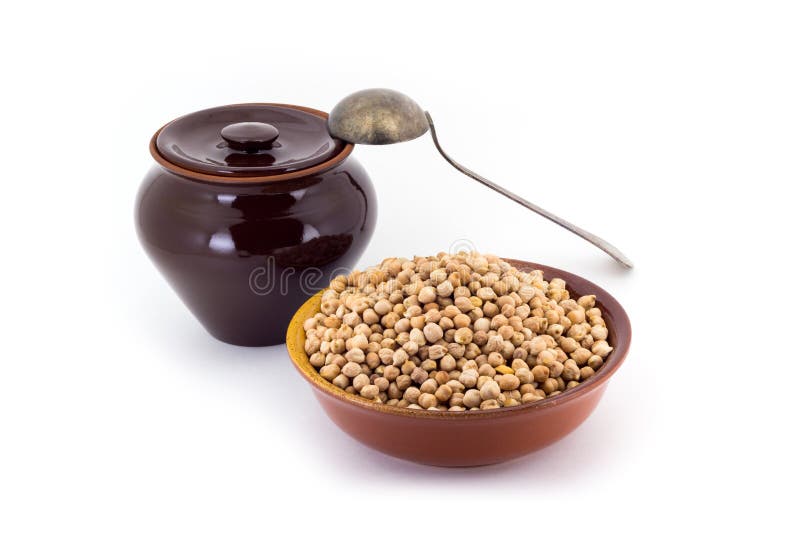The composition of chick peas in a clay pial next to a clay pot and a copper spoon,. Still life of chick peas in ceramic pial, ceramic pot, old spoon , isolated stock photography