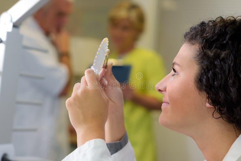 Dental technician looking at prosthesis royalty free stock photography