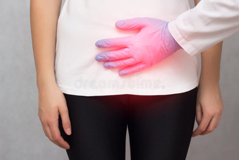 A doctor in medical gloves holds a girl by the lower abdomen which has problems with menstruation and pain, carcinoma. A doctor in medical gloves holds a girl by stock photos