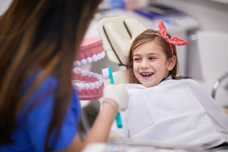 Education in dental office, correct teeth brushing. Smiling girl stock photography