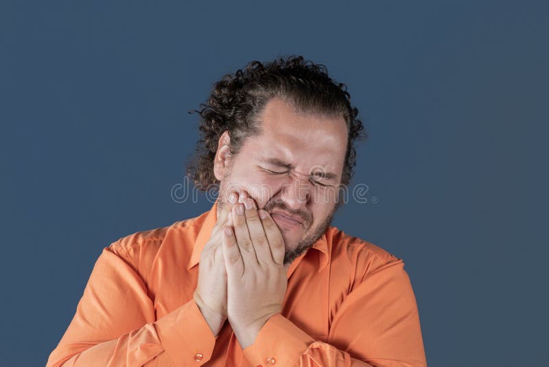 A fat man holds on to his cheek and winces in pain. Toothache and health problems. A fat man holds on to his cheek and winces in pain stock images