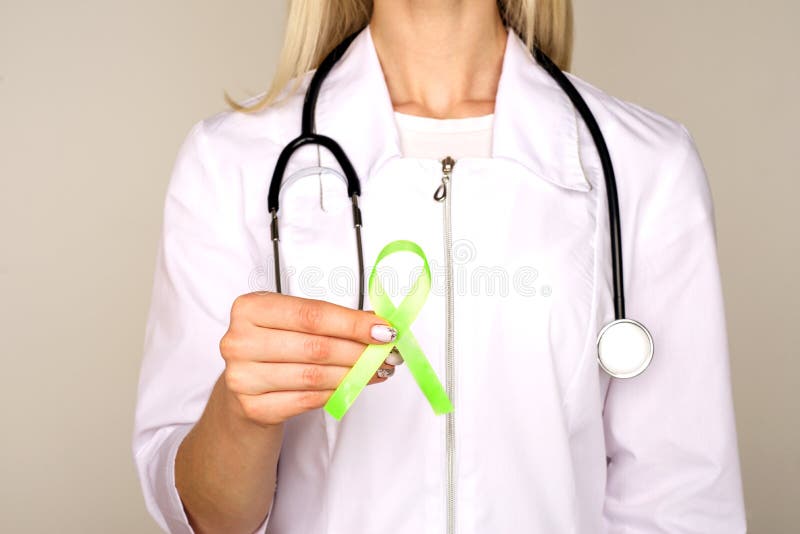 Female doctor in white uniform with light green ribbon awareness in hand for Celiac Disease, Chronic pelvic Pain, Human Papilloma. Virus, Sexually Transmitted royalty free stock photography