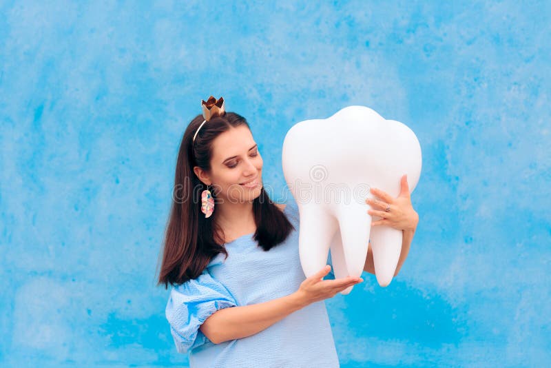 Woman in Tooth Fairy Costume Holding Big Molar. Funny princess holding an oversized fallen baby tooth stock photography