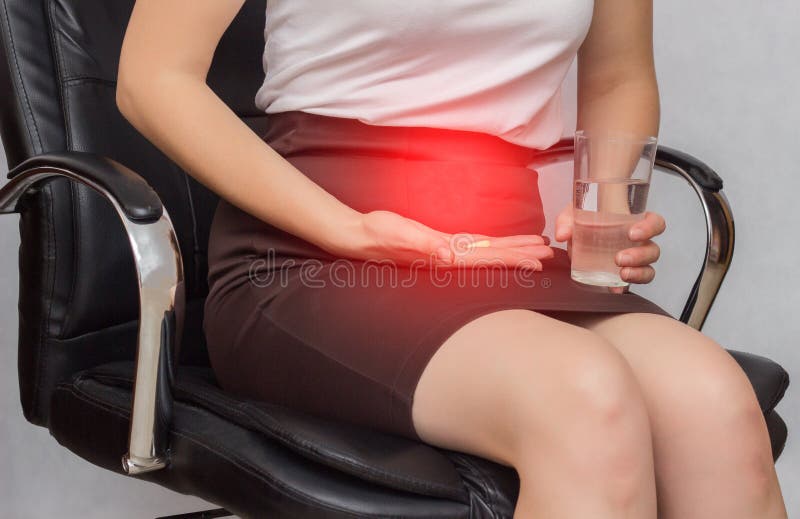 A girl sits in an office chair and holds a pill for pain in menstruation, business, close-up, anti-inflammatory. A girl sits in an office chair and holds a pill stock photo