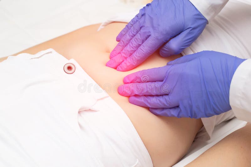 A gynecologist doctor probes the lower abdomen of a girl who has pain and inflammation of the reproductive system. Ovarian cyst,. A gynecologist doctor probes stock photo
