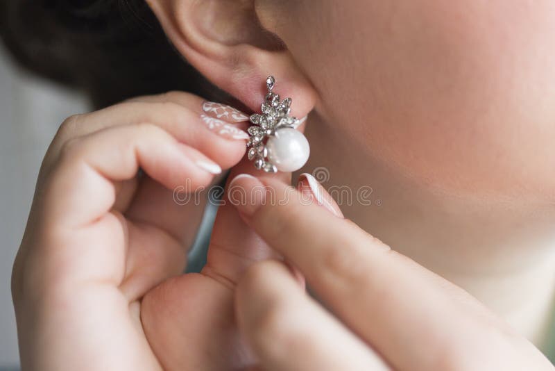 Hands of girl wearing pearl earrings stock image