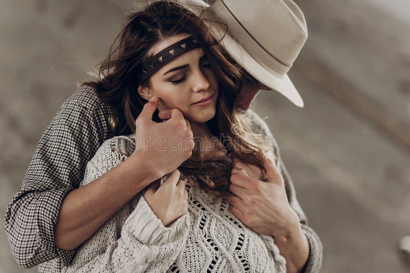 Handsome cowboy man in white hat touching cheek of beautiful boho gypsy woman with leather headband, face closeup portrait. Handsome cowboy men in white hat stock image