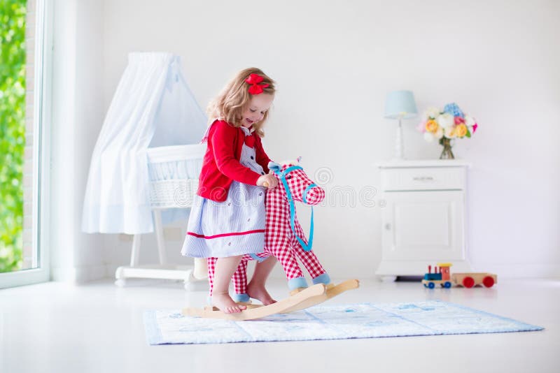 Little girl riding a toy horse royalty free stock photos