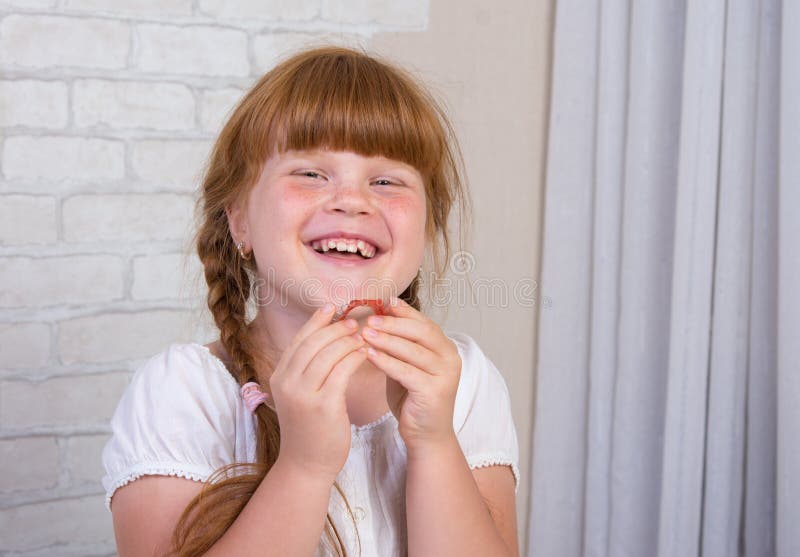 Little red-haired girl in a white dress holds a plate in her hands to correct a bite of teeth. Little red-haired girl in a white dress holds a plate in her hands stock photos