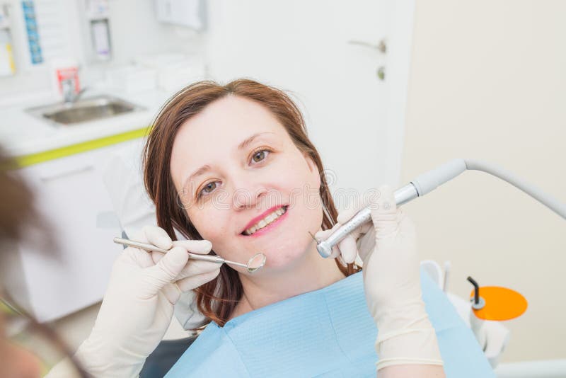 Middle aged woman patient at the dentist drilling the tooth with a turbine and making dental fillings stock images