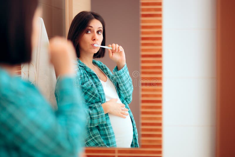 Pregnant Woman Wearing Pajamas Brushing her Teeth. Mother to be being careful with oral hygiene during pregnancy royalty free stock images