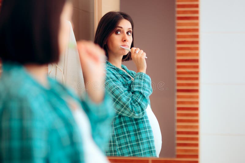 Pregnant Woman Wearing Pajamas Brushing her Teeth. Mother to be being careful with oral hygiene during pregnancy stock photography