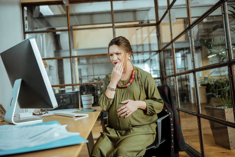 Pregnant woman having strong toothache at work. Strong toothache. Pregnant beautiful mature woman having strong toothache at work stock image