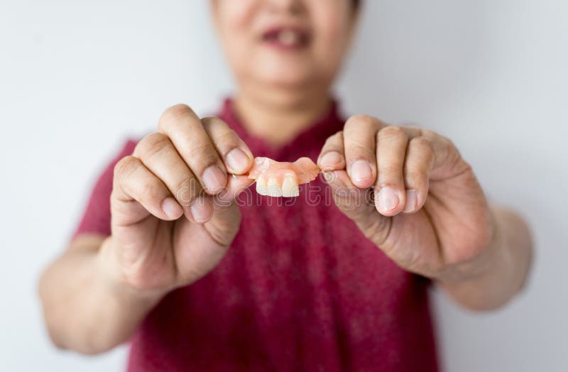 Senior asian woman is holding dentures in hands,Dental prosthesis,False teeth,Close up stock photos