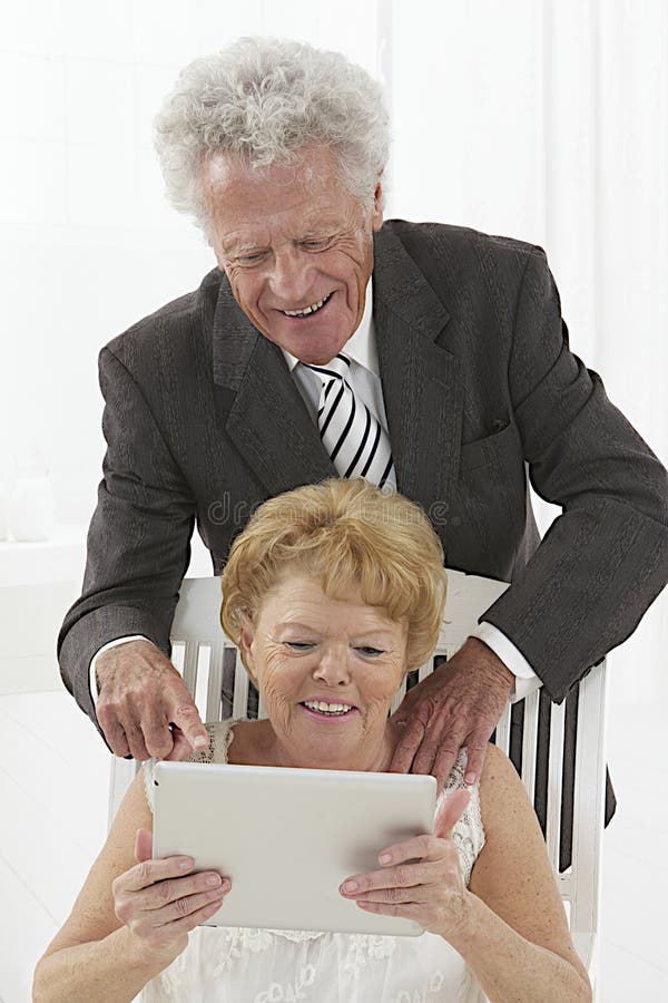 Senior couple with tablet device. Senior couple looking at web pages or photos, on electronic tablet , the husband is splinting something stock photos