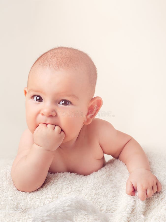 Small cute funny baby infant teething with face expression hands and fingers in mouth sore gums. Soothe royalty free stock photography