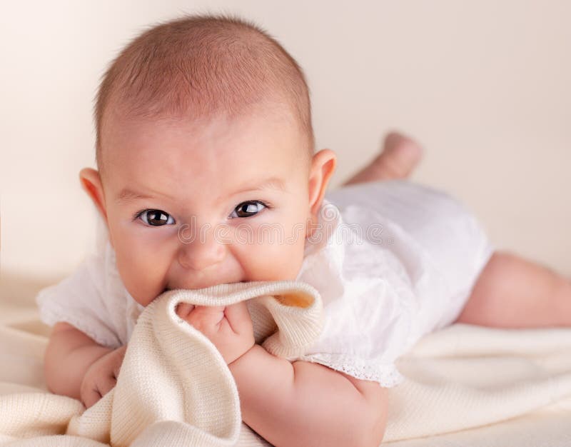 Small cute funny baby infant teething with face expression hands and fingers in mouth sore gums. Soothe stock photo