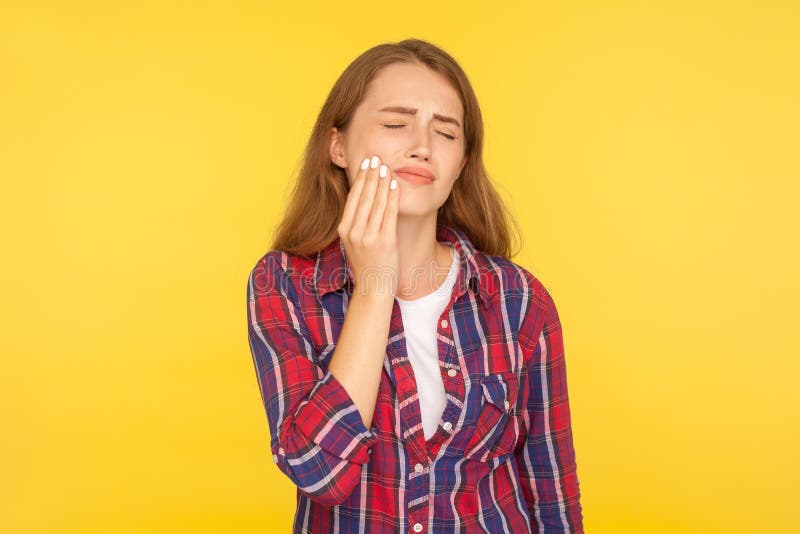 Toothache. Portrait of unhealthy girl in checkered shirt touching sore cheek, grimacing from sudden pain having dental problems. Sensitive teeth or decay stock photos