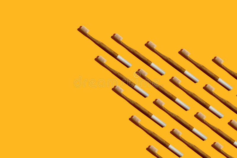 Wedge or arrow shaped bamboo toothbrushes on yellow background stock photos