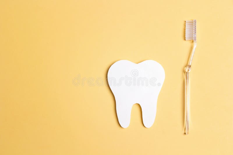 White paper tooth with toothbrush on yellow background. Dental health concept. Dentist day concept stock image