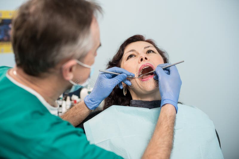 Woman having dental check up in dental office. Dentist examining a patient`s teeth with dental tools stock image