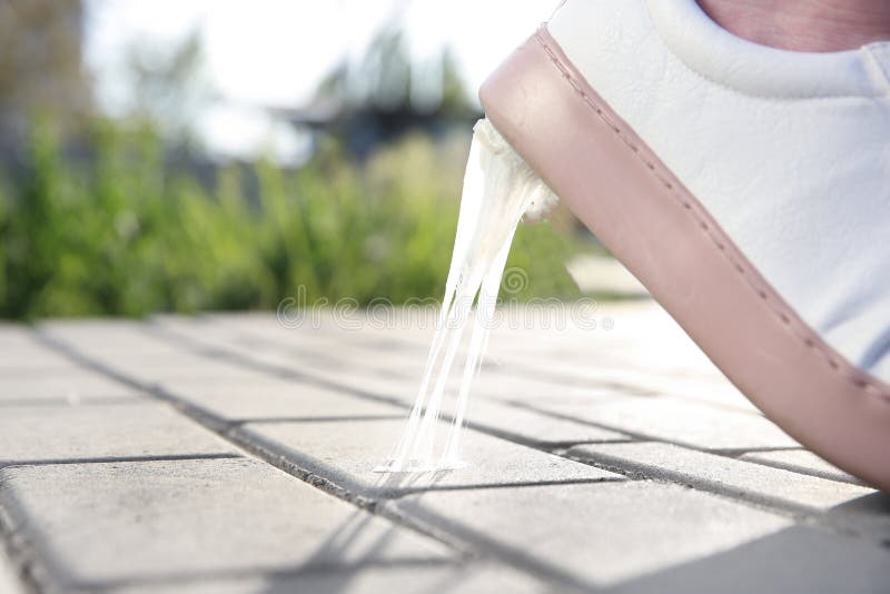 Woman stepping in chewing gum on sidewalk. Concept of stickiness stock image
