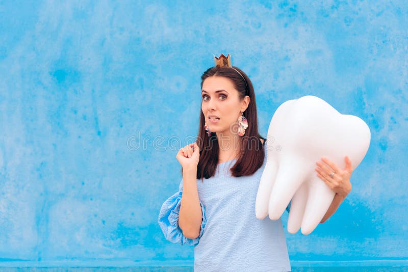 Woman in Tooth Fairy Costume Holding Big Molar. Funny princess holding an oversized fallen baby tooth stock images