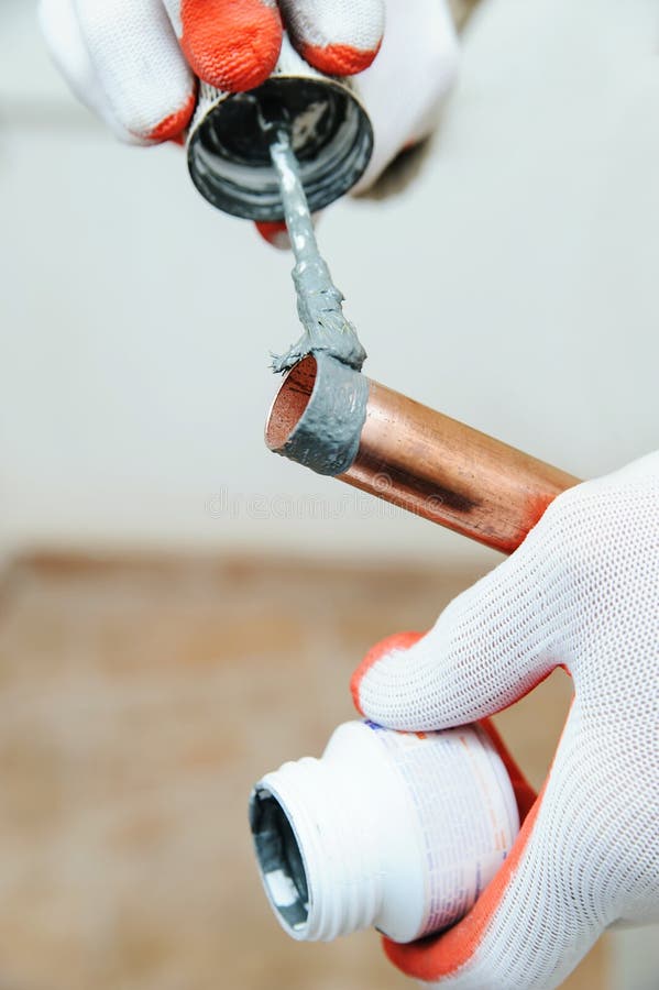 A worker is applying flux. A worker is applying flux to the outside of the copper tube stock photos