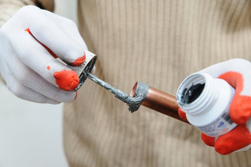 A worker is applying flux. A worker is applying flux to the outside of the copper tube stock photo