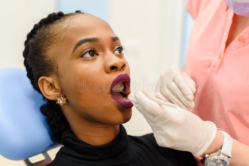 Young black woman with female dentist doctor during tooth examination and treatment stock photo