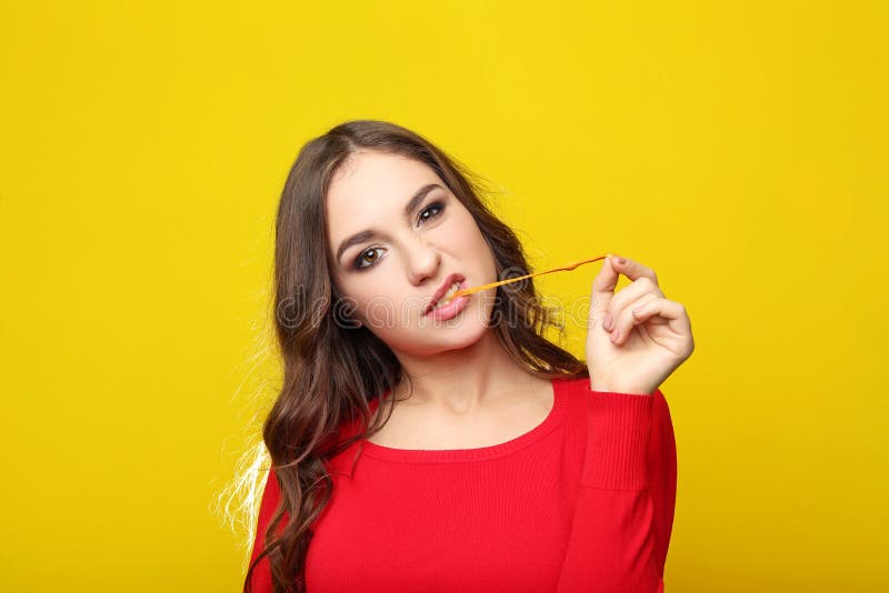 Young girl chewing gum. Beautiful young girl chewing gum on yellow background royalty free stock photo