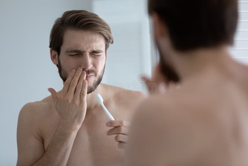 Young man suffer from gums inflammation brushing teeth stock photos
