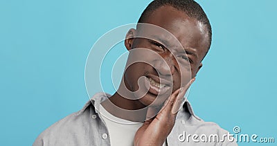 Emotional guy with toothache touching his sore cheek. Oral care problem. Emotional guy with toothache touching his sore cheek, blue studio background stock video