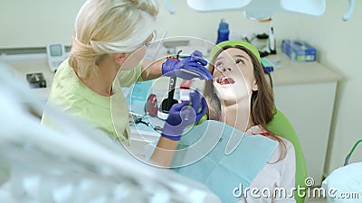 Stomatology doctor working in dental clinic. Female patient on review of dentist. Female dentist taking out cotton tampon from open patient mouth. Dental stock video footage