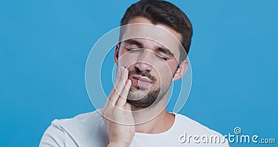 Young man suffering from strong tooth pain. Teeth problem. Young man suffering from strong tooth pain, blue studio background stock footage